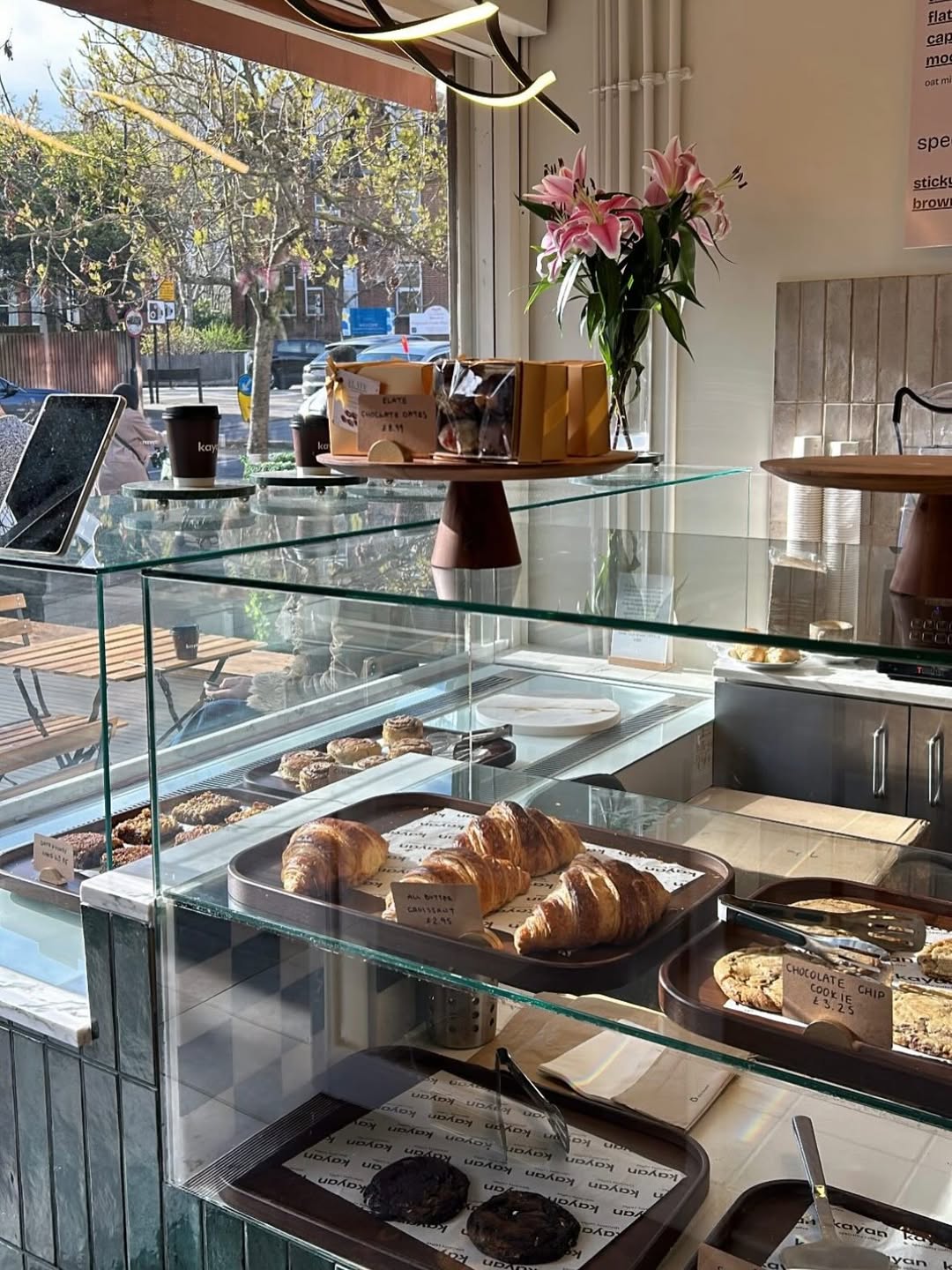 Inside Kayan Coffee — the display counter with croissants and flowers
